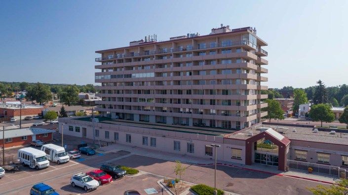 A multi-story apartment building with a parking area in an urban setting.