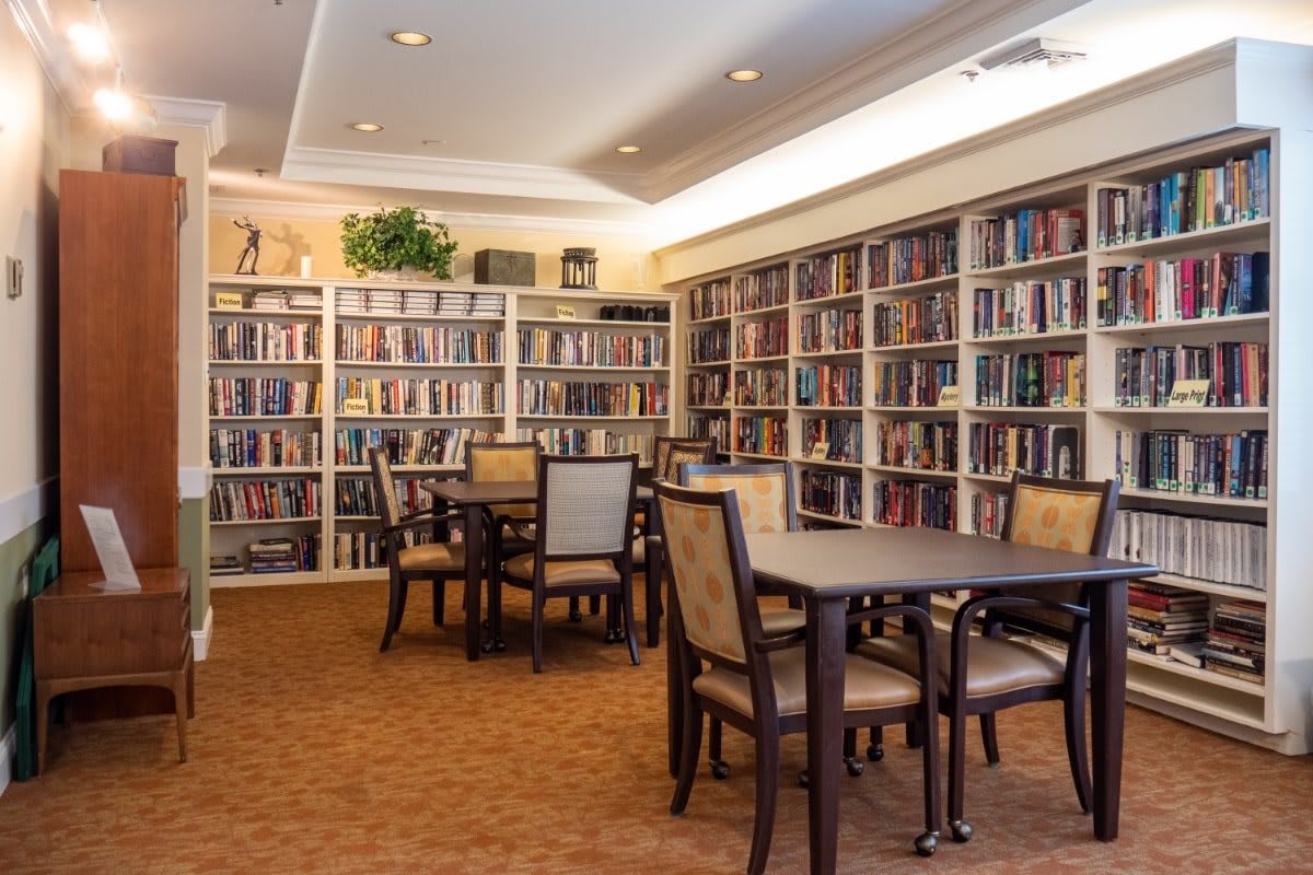 A cozy library with bookshelves lining the walls and seating areas for reading.