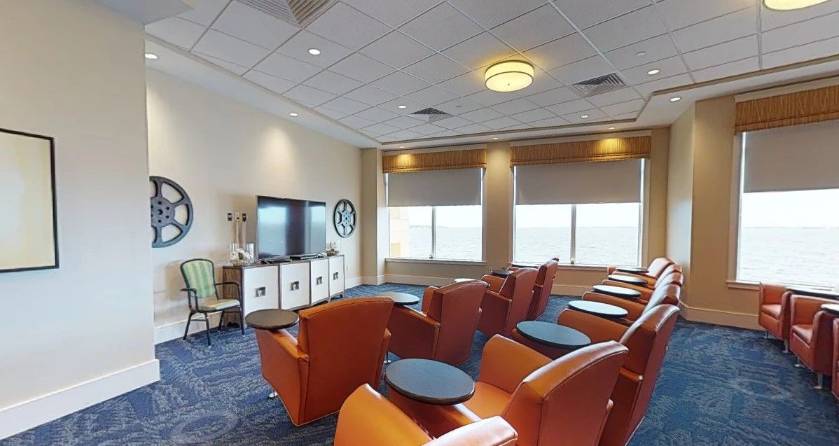 A well-lit room with comfortable seating and a television, featuring large windows.