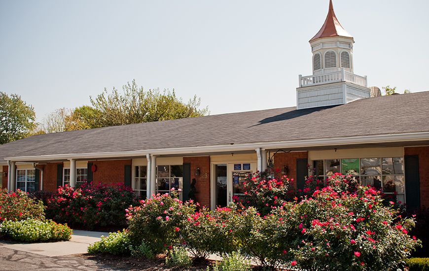 A charming building with a cupola and a vibrant garden in front.