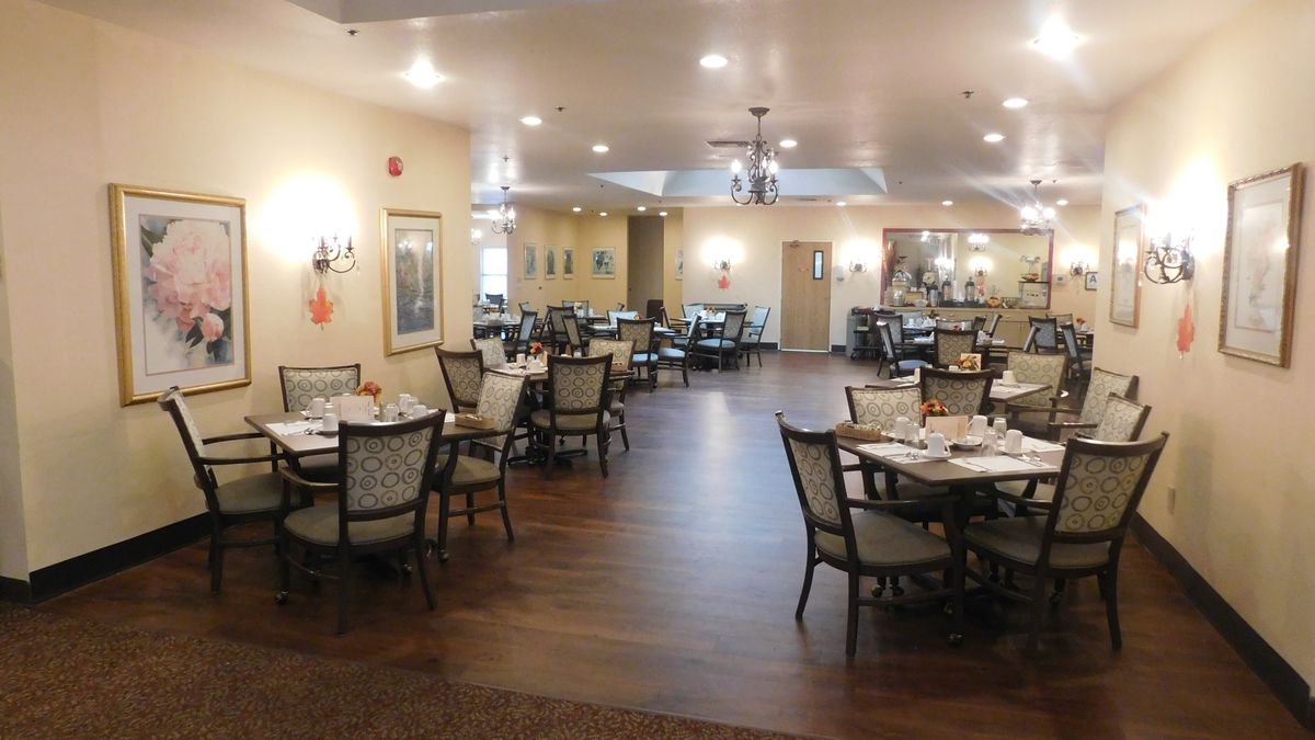 An elegant dining room set with tables and chairs, featuring warm lighting and tasteful decor.