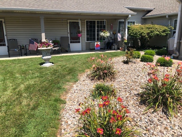 A well-maintained backyard garden with various flowers, rocks, and a cozy patio area.
