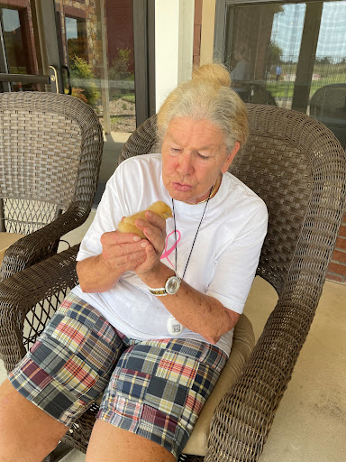 An elderly woman enjoying a moment with her pet in a relaxed outdoor setting.