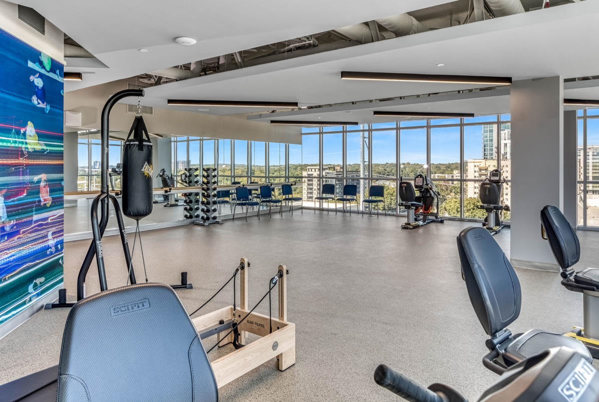 A spacious fitness center with modern exercise equipment and large windows providing ample natural light.