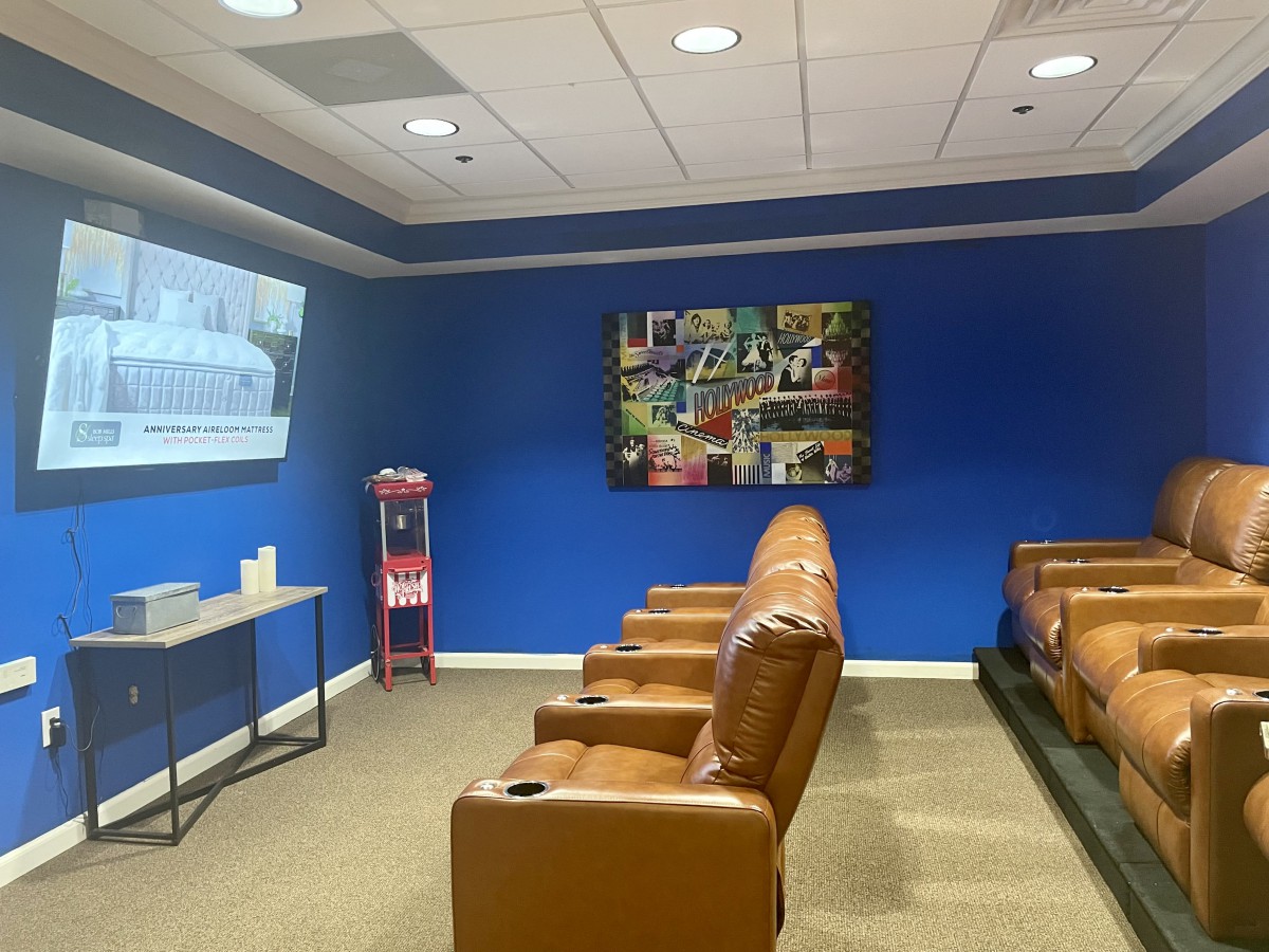 A cozy home theater room with leather seating, a projector screen, and a popcorn machine against blue walls.