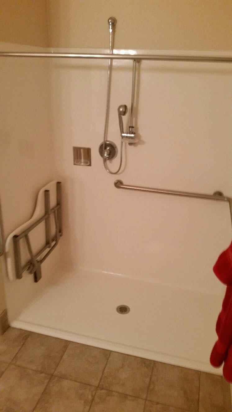 An accessible shower with handrails and a grab bar.