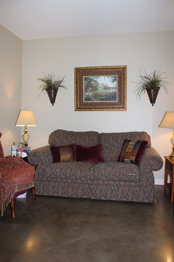 A cozy living room featuring a patterned sofa, decorative plants, and warm lighting.