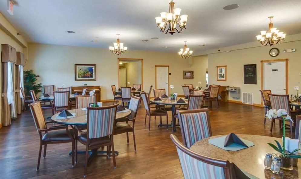 A spacious and elegantly designed dining room with chandeliers, round tables, and comfortable chairs.