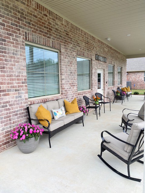 A cozy patio area with comfortable seating and decorative cushions, set against a brick wall with large windows.