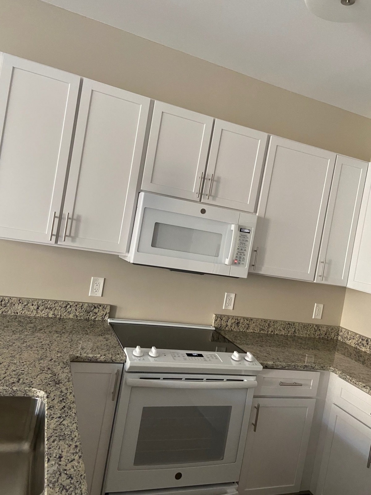 A modern kitchen with white cabinets and granite countertops.