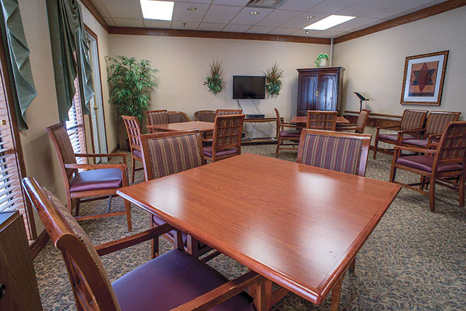A well-furnished meeting room with tables, chairs, and a television.