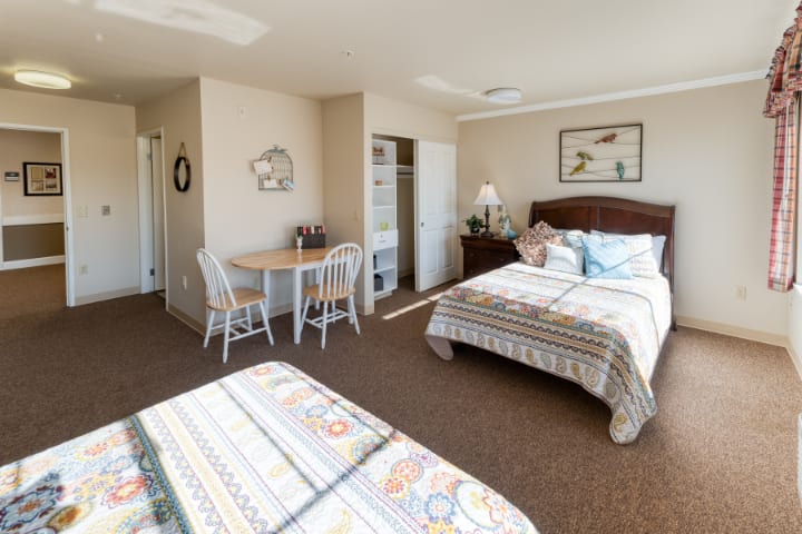 A cozy hotel room with two double beds, a small dining table, and simple decor.