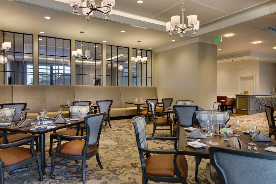 An elegant dining room with neatly arranged tables and chairs, adorned with chandeliers.