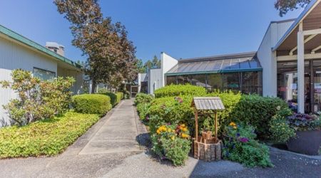 A well-maintained building surrounded by lush gardens and a clear blue sky.