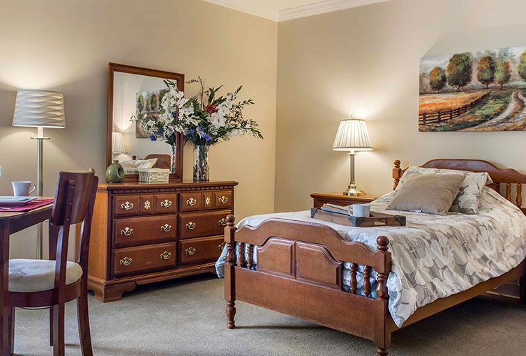 A cozy, well-decorated bedroom featuring a wooden bed and dresser with a beautiful flower arrangement.