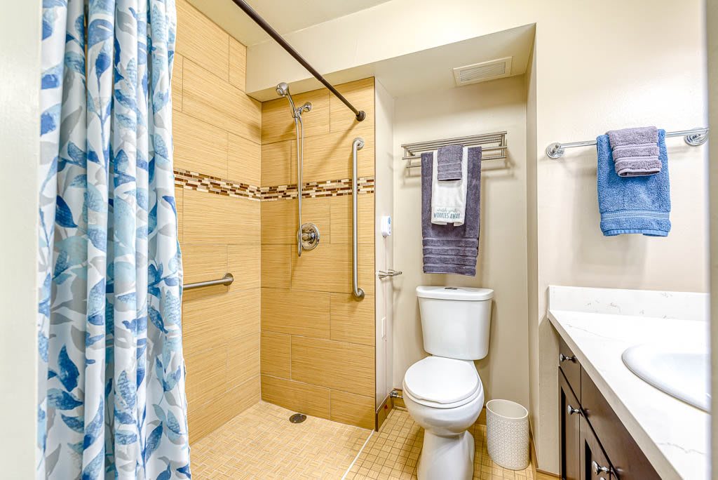 A modern bathroom featuring a shower, toilet, and sink with neatly arranged towels.