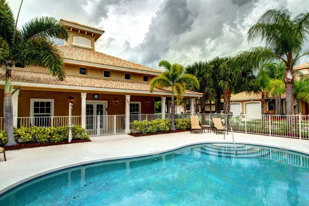 A tropical vacation home with a swimming pool and palm trees.