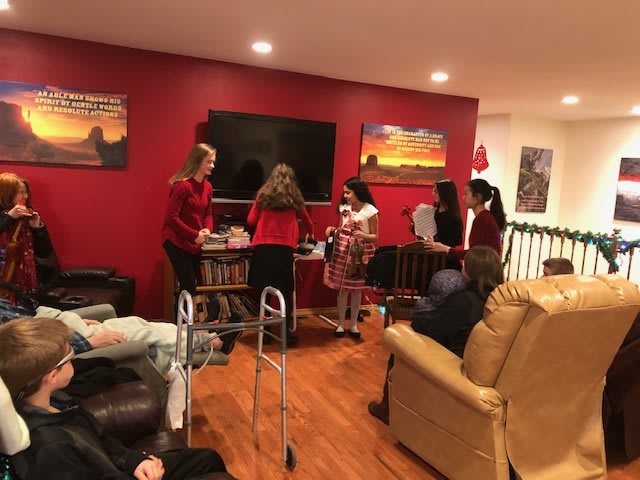 A group of people gathered in a cozy living room with red walls and a television.