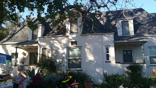 A charming residential house with a garden and trees in the foreground.
