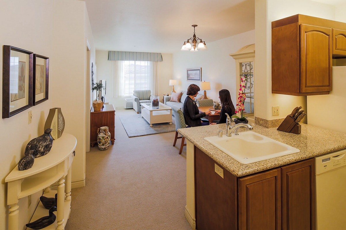 A cozy living area with an open kitchen where two people are engaged in conversation.