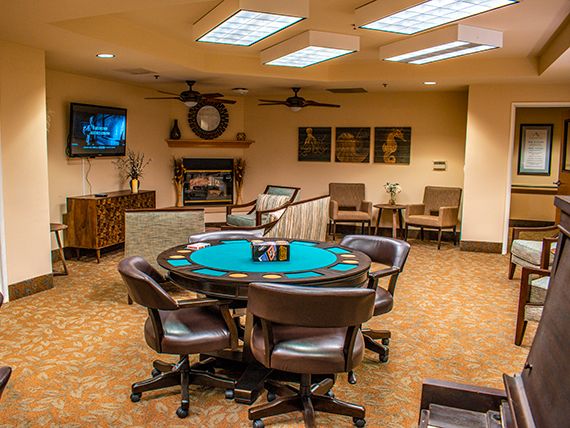 A cozy game room featuring a poker table surrounded by chairs, with a television mounted on the wall.