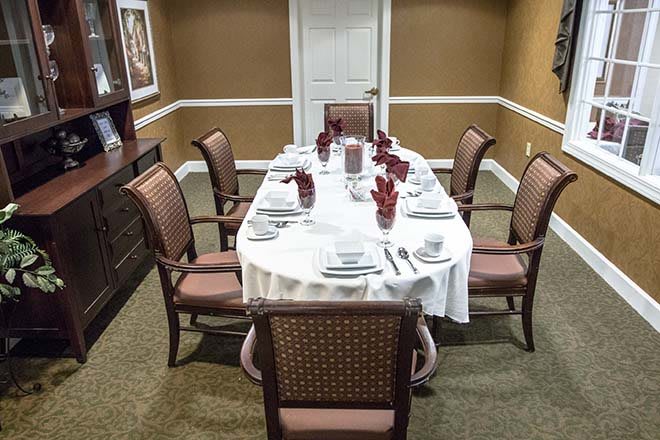 A formal dining room setup with a white tablecloth and neatly arranged place settings for six.