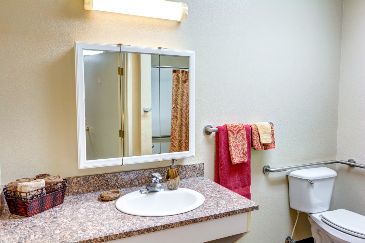 A clean bathroom with a sink, mirror, and neatly arranged towels.