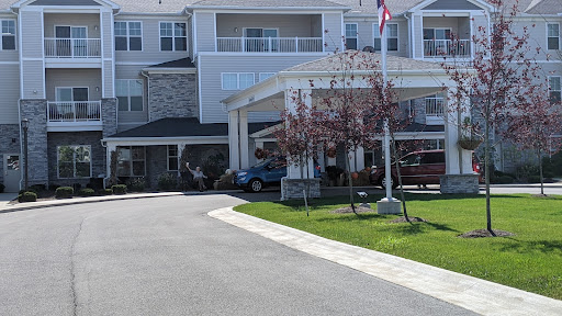 A welcoming entrance to a residential building with landscaped grounds and a prominent flag.