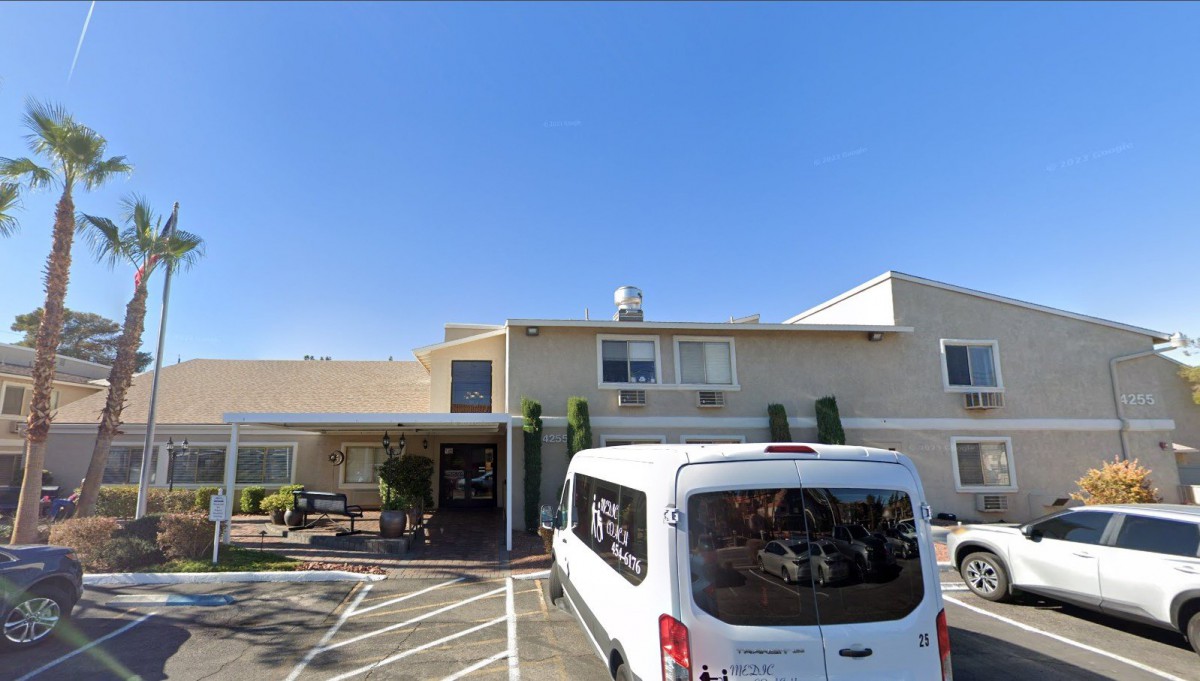 A white van parked in front of a hotel building with a clear blue sky.