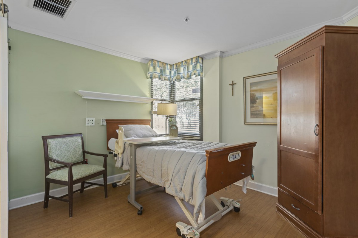 A tidy hospital room with a bed, chair, and window.
