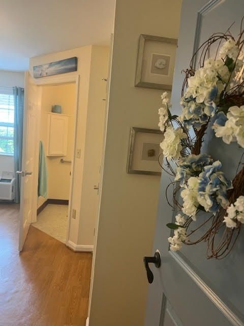 A hallway with a floral wreath on the door, leading to a bathroom.