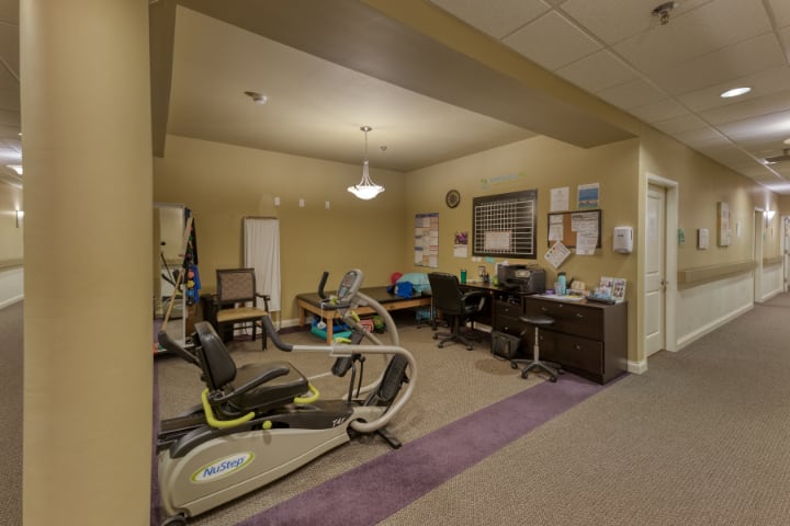 A physical therapy room with exercise equipment and office furniture.