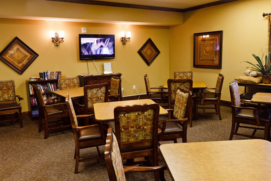 A cozy dining area with multiple tables and chairs, featuring a wall-mounted television and elegant decor.