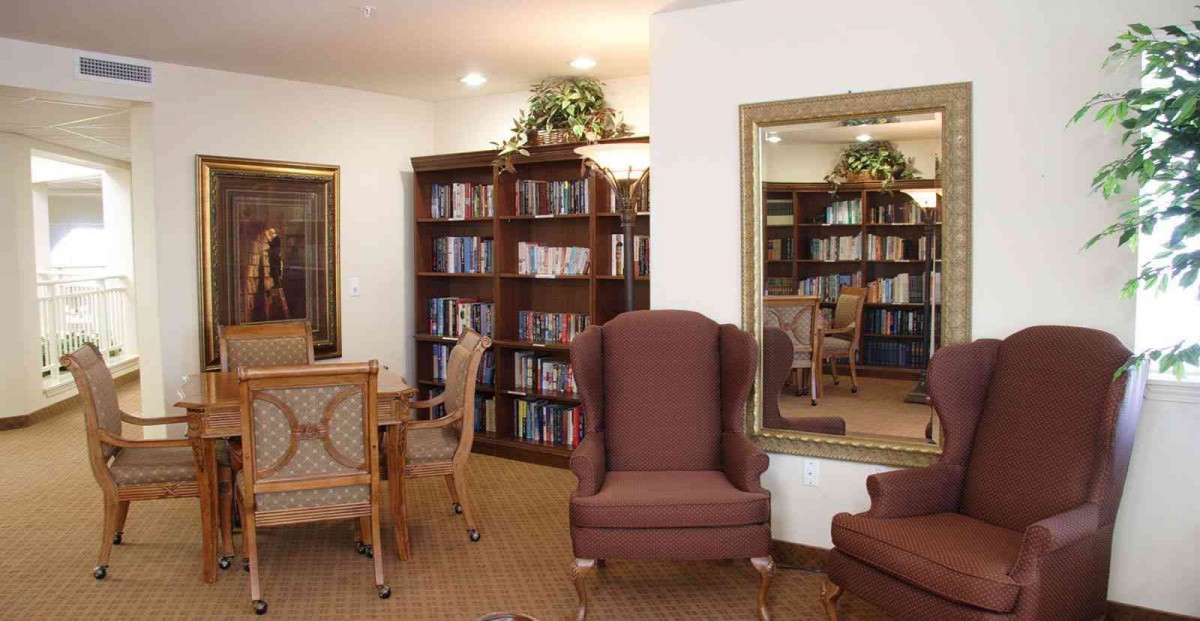 A cozy library corner with armchairs, bookshelves, and a large mirror.