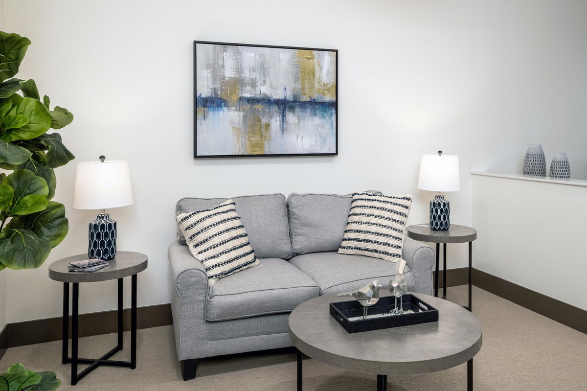 A cozy living room with a gray sofa, abstract wall art, and side tables with lamps.