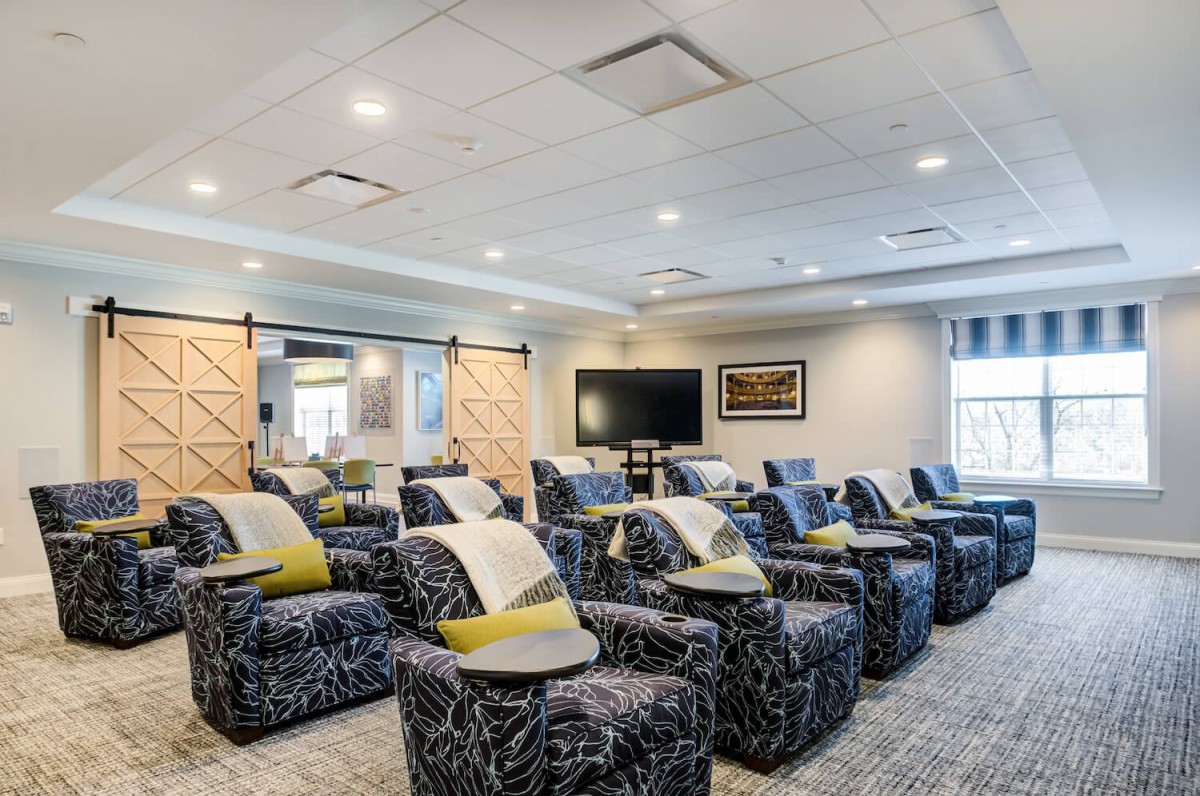 A modern theater room featuring multiple recliner chairs arranged in rows facing a large screen.