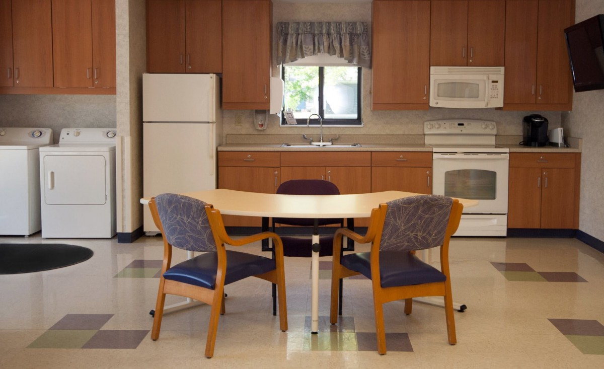 A kitchen area with a table, chairs, refrigerator, and oven.