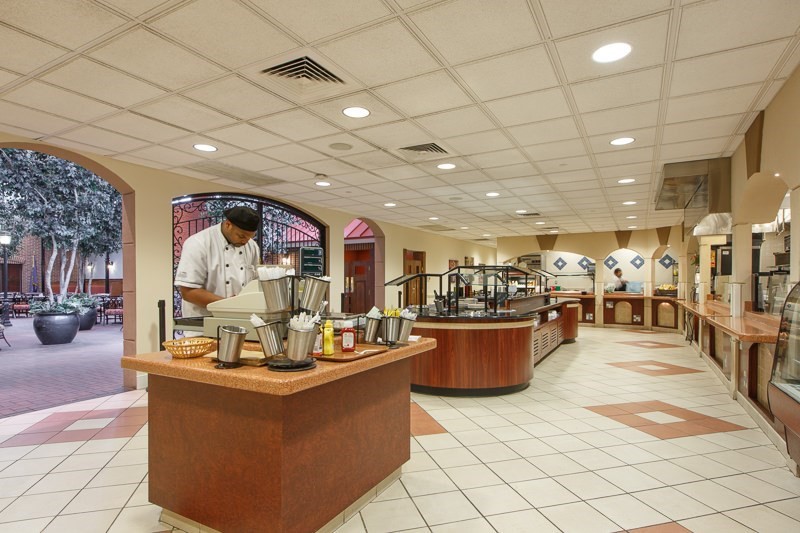 A spacious buffet restaurant with a chef preparing food at a central station.
