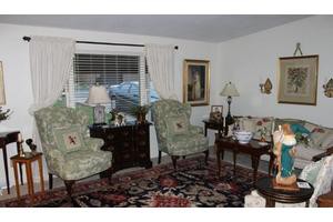 A cozy living room featuring floral armchairs, a patterned rug, and elegant decor.