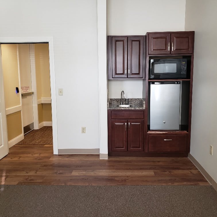A compact kitchenette with wooden cabinets and modern appliances in a small apartment.