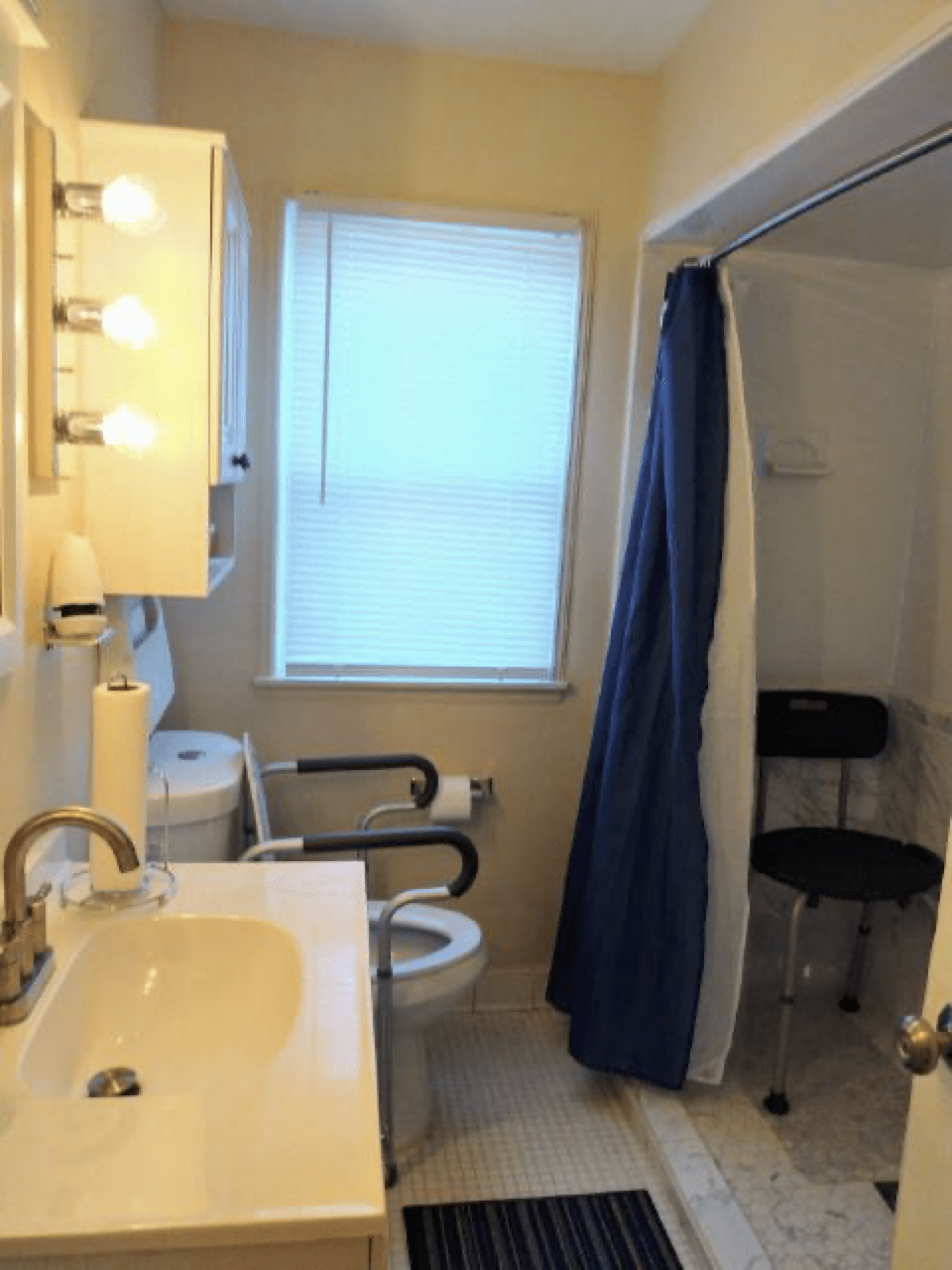 A bathroom with a sink, toilet, and shower area equipped with accessibility features.