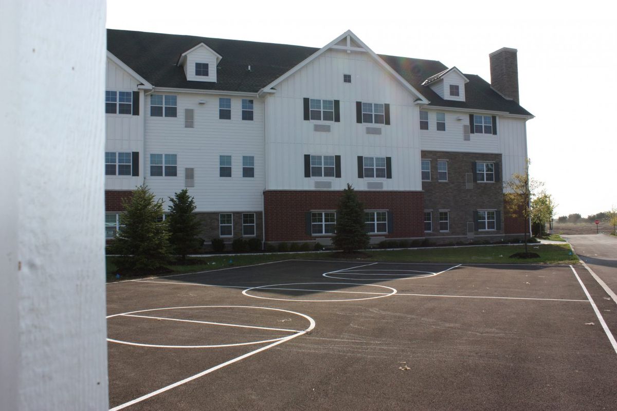 A three-story residential building with a parking area in front.