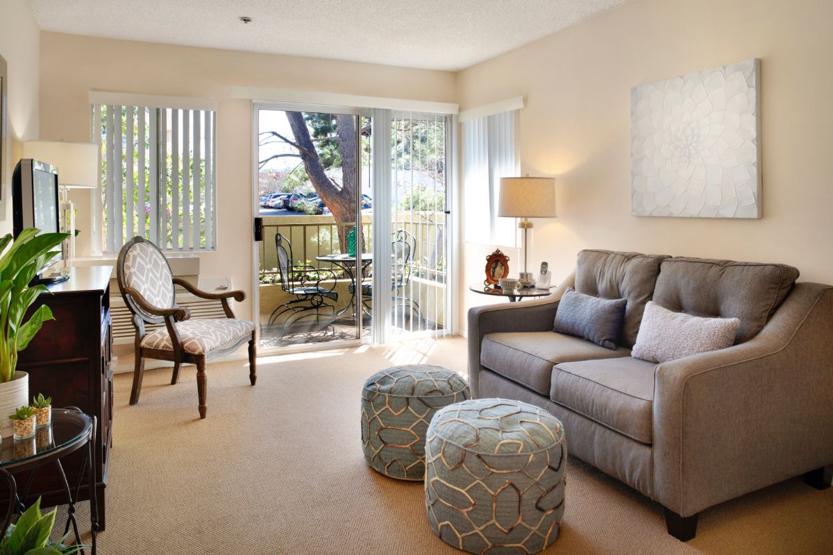 A cozy living room with a sofa, armchair, and sliding glass doors leading to a patio.