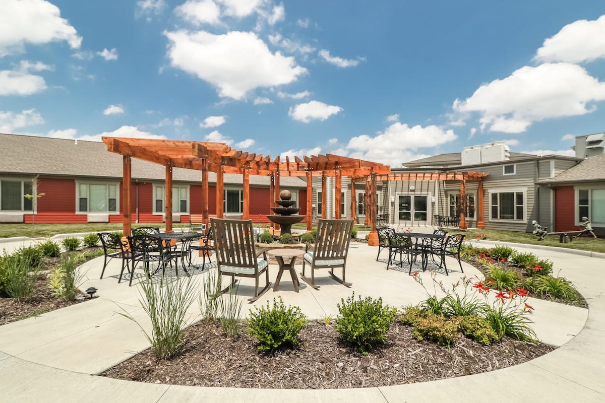 A beautifully landscaped courtyard featuring outdoor furniture and a pergola.