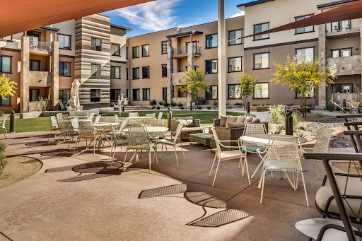 A stylish outdoor lounge area in a modern apartment complex, featuring comfortable seating and landscaped grounds.