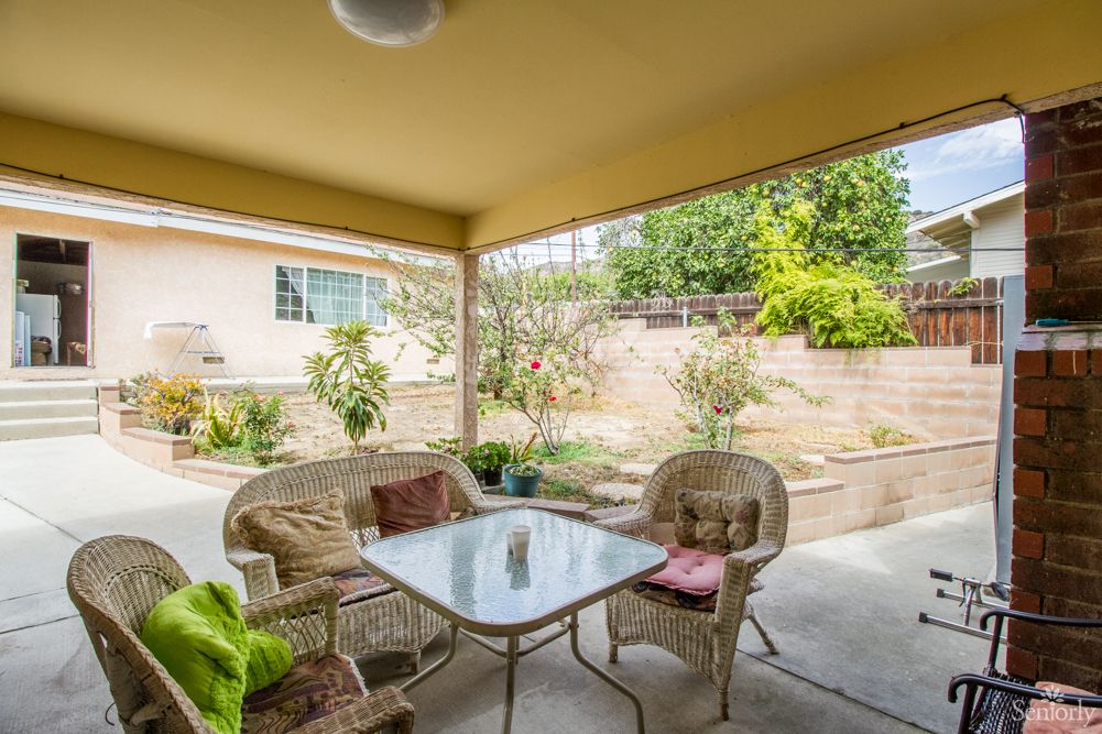 A cozy patio with wicker furniture overlooking a garden.