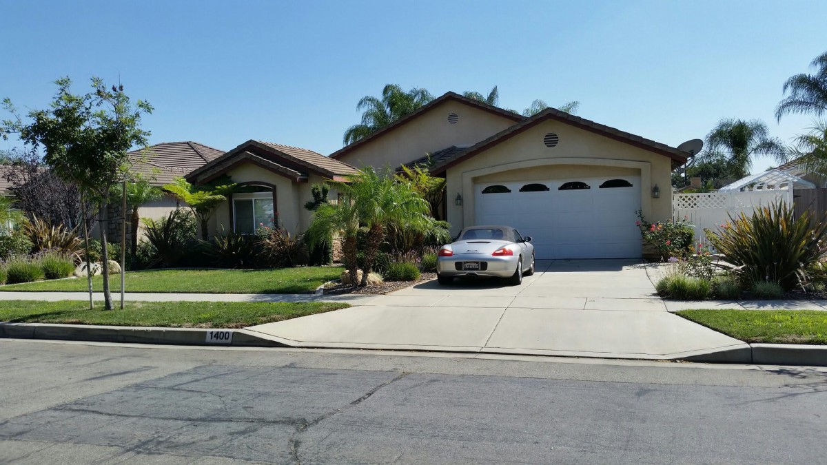 A suburban house with a car parked in the driveway on a sunny day.
