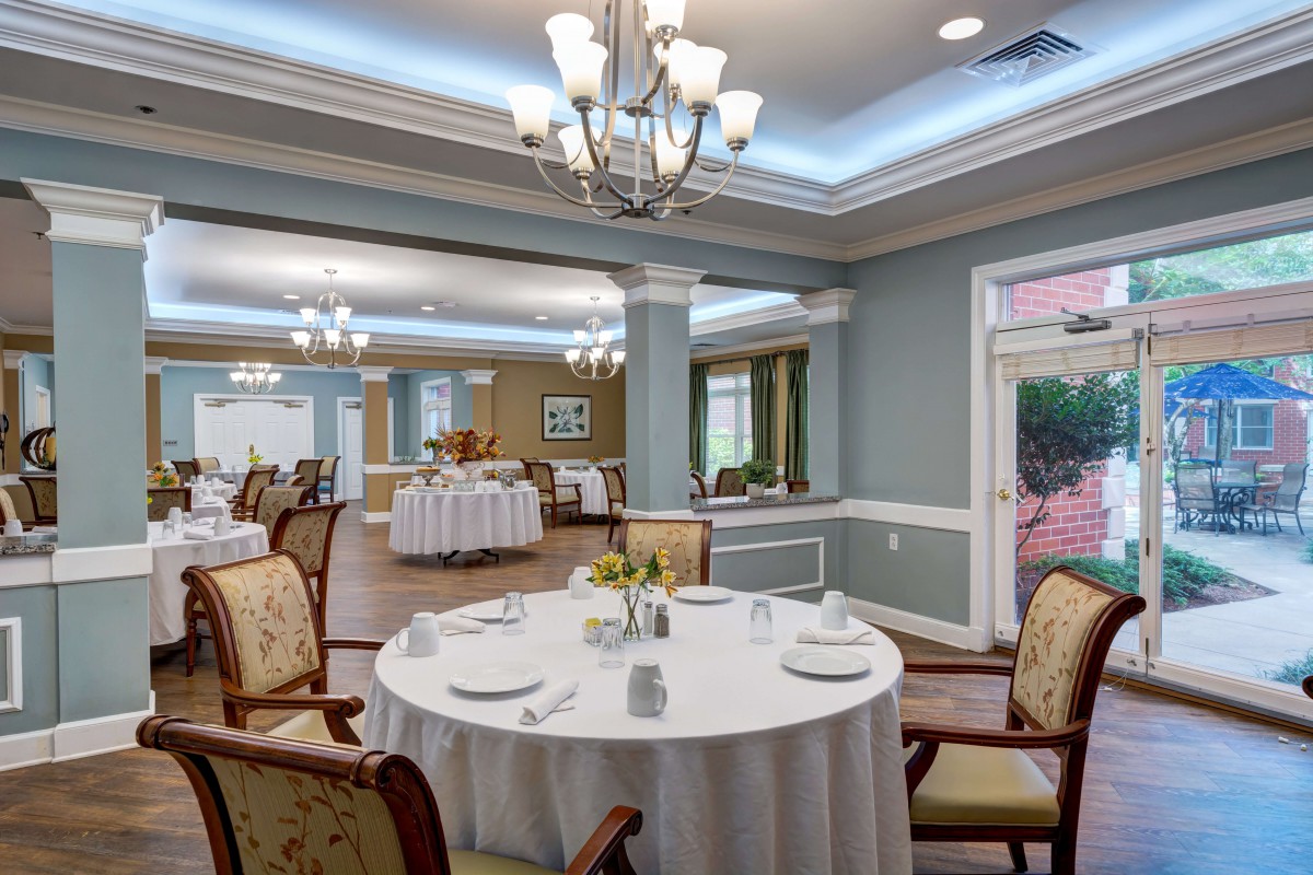 An elegant dining room with formal table settings and chandeliers.