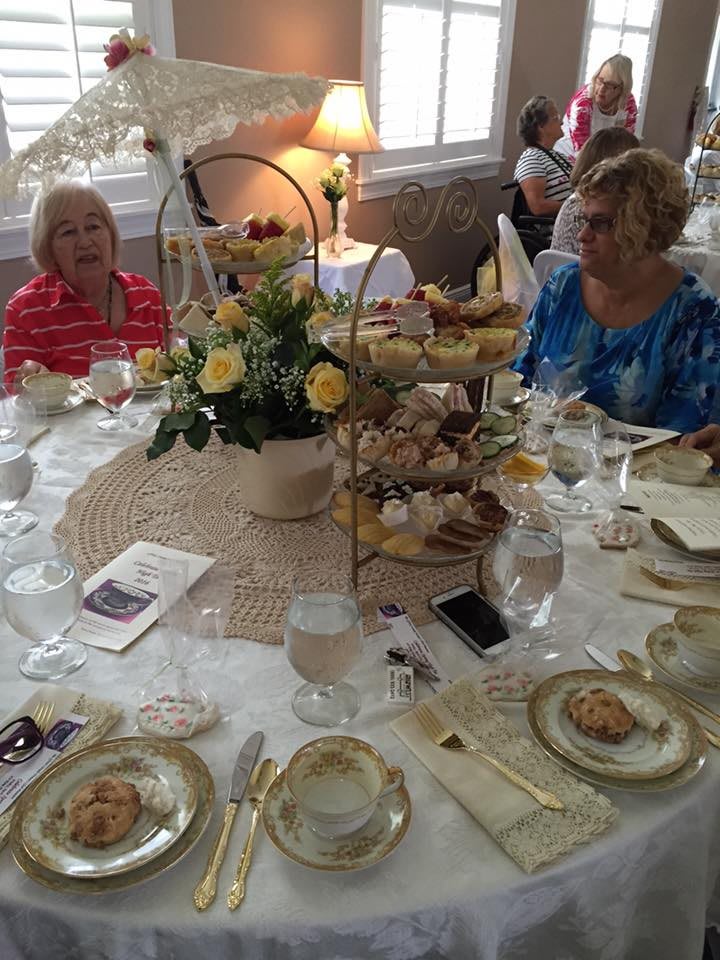 A group of friends enjoying afternoon tea with an elegant table setting and assorted pastries.
