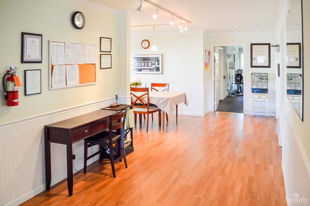 A bright and welcoming interior with wooden flooring, featuring a desk, chairs, and wall decorations.